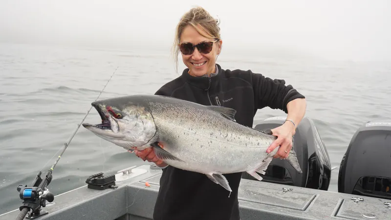 A guest holding a silver salmon on the boat